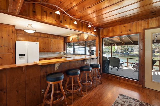 kitchen with white refrigerator with ice dispenser, dark hardwood / wood-style flooring, plenty of natural light, and wooden ceiling