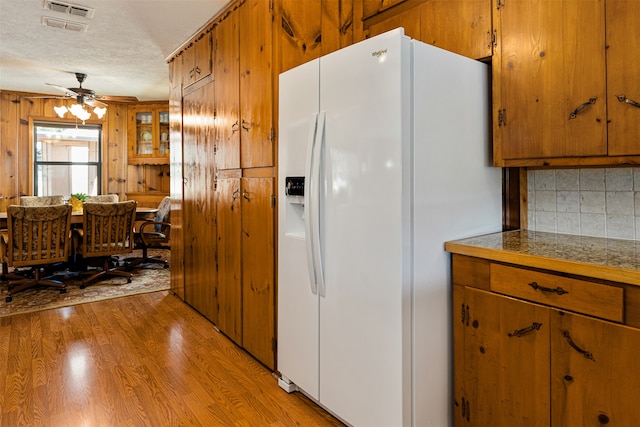 kitchen with tasteful backsplash, ceiling fan, wooden walls, light hardwood / wood-style flooring, and white fridge with ice dispenser