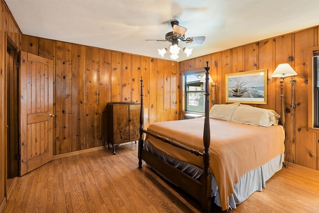 bedroom with wood-type flooring, ceiling fan, and wooden walls