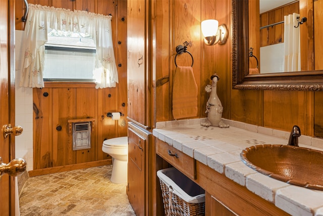 bathroom with vanity, toilet, and wood walls