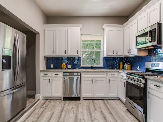 kitchen featuring sink, white cabinets, light hardwood / wood-style floors, and appliances with stainless steel finishes