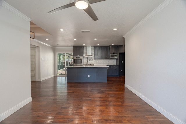 kitchen featuring dark hardwood / wood-style flooring, an island with sink, wall chimney range hood, and appliances with stainless steel finishes