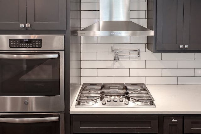 kitchen with backsplash, wall chimney exhaust hood, and appliances with stainless steel finishes