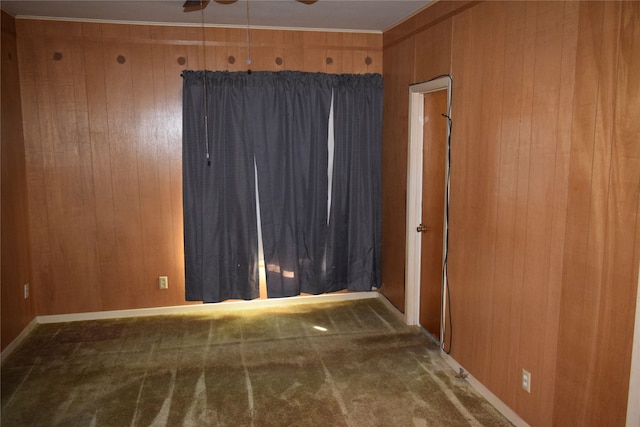 unfurnished room with wooden walls, carpet, and ceiling fan