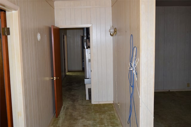 hall featuring dark carpet and wooden walls