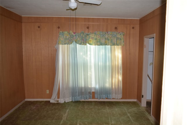 unfurnished room featuring carpet, ceiling fan, and wood walls