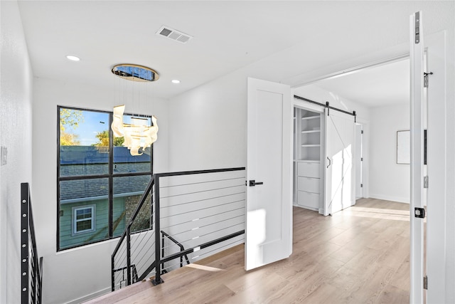 hall with light hardwood / wood-style floors and a barn door