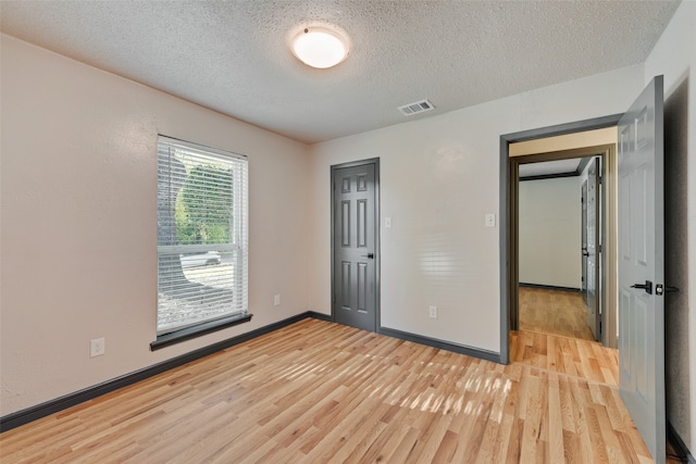 unfurnished bedroom featuring a textured ceiling, light hardwood / wood-style floors, and a closet