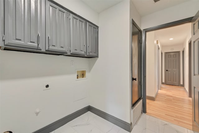 laundry area featuring hookup for an electric dryer, washer hookup, light hardwood / wood-style floors, and cabinets