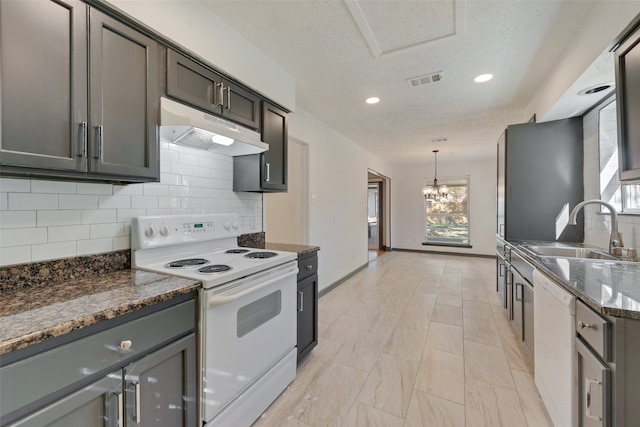 kitchen with hanging light fixtures, white appliances, sink, and a wealth of natural light