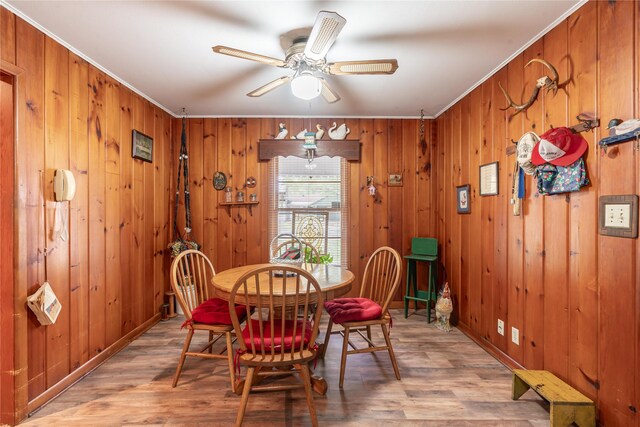 dining space featuring wood walls, light hardwood / wood-style floors, and ornamental molding