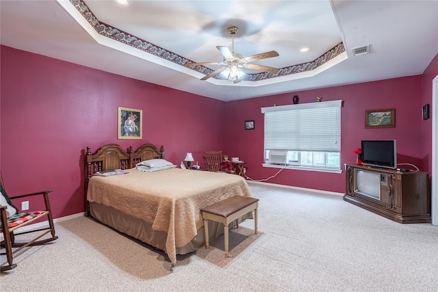 carpeted bedroom with a raised ceiling and ceiling fan