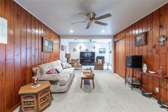 living room with light colored carpet, crown molding, ceiling fan, and wooden walls