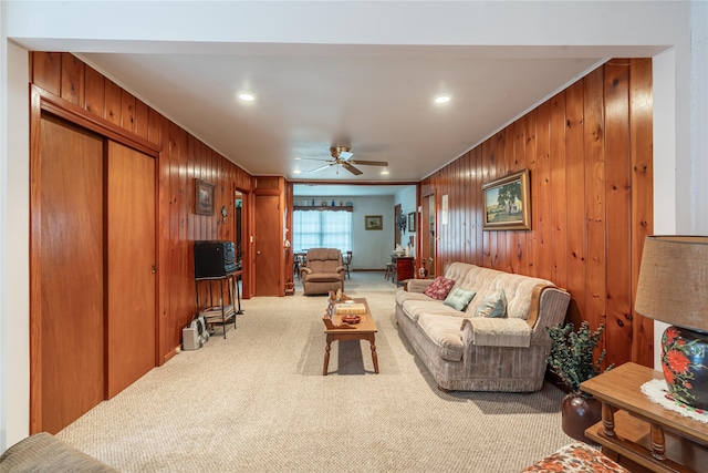 living room featuring crown molding, carpet, wood walls, and ceiling fan