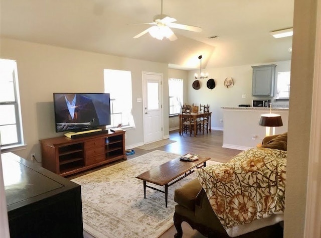 living room with vaulted ceiling, ceiling fan, and light wood-type flooring