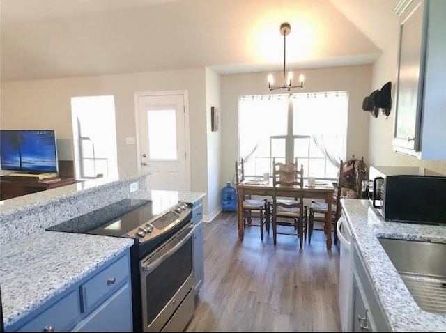 kitchen with light stone counters, electric range, a notable chandelier, pendant lighting, and light hardwood / wood-style floors