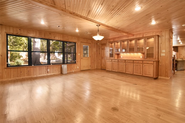 unfurnished living room with beam ceiling, wood walls, light hardwood / wood-style flooring, and wooden ceiling