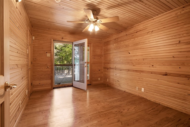 empty room featuring light wood-type flooring, ceiling fan, wooden ceiling, and wood walls