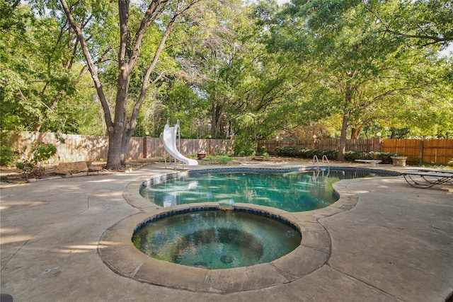 view of swimming pool featuring an in ground hot tub, a patio, and a water slide