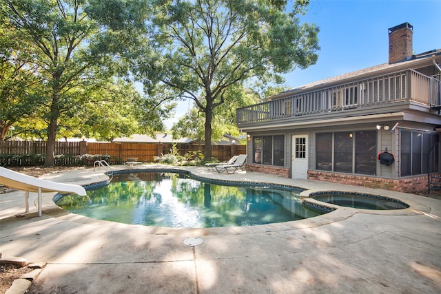 view of swimming pool featuring an in ground hot tub and a water slide