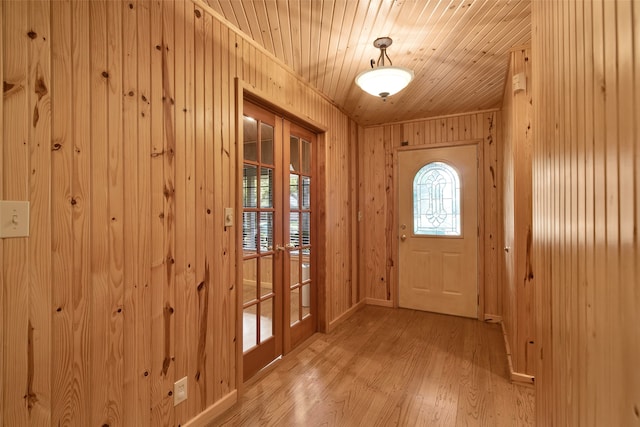 entryway featuring wood ceiling, light wood-type flooring, wooden walls, and french doors