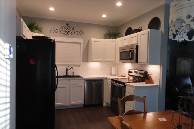 kitchen featuring dark wood-type flooring, sink, decorative backsplash, appliances with stainless steel finishes, and white cabinetry