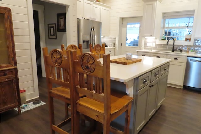 kitchen featuring sink, white cabinetry, stainless steel appliances, dark hardwood / wood-style flooring, and decorative backsplash