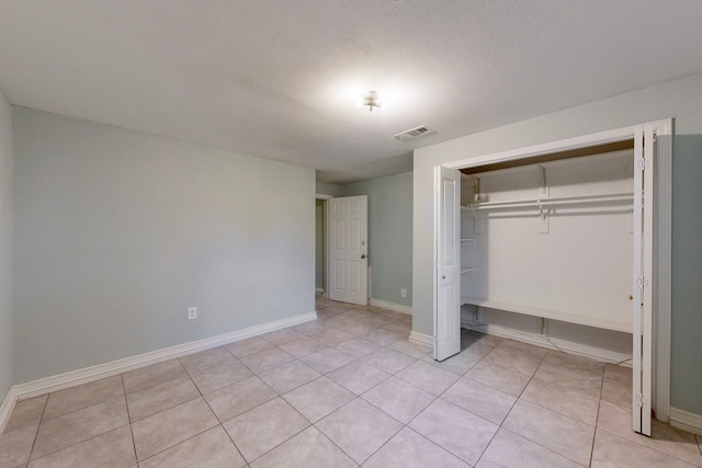 unfurnished bedroom featuring a closet, light tile patterned flooring, and a textured ceiling