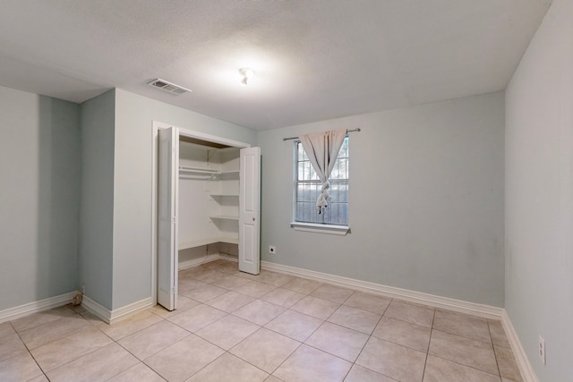 unfurnished bedroom featuring a closet, light tile patterned floors, and a textured ceiling