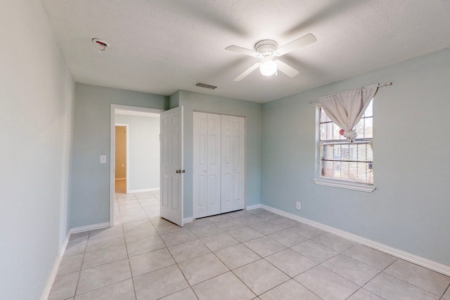 unfurnished bedroom featuring light tile patterned floors, a textured ceiling, a closet, and ceiling fan