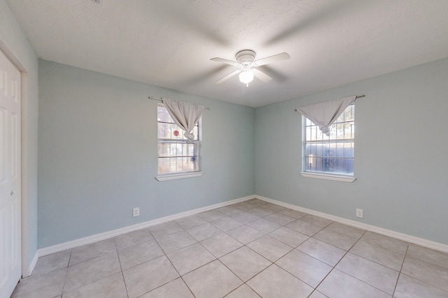 spare room with light tile patterned floors, a wealth of natural light, and ceiling fan