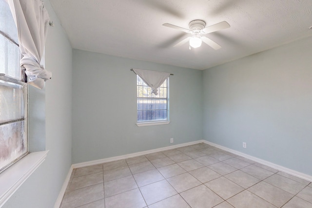 empty room featuring ceiling fan, light tile patterned floors, and a textured ceiling