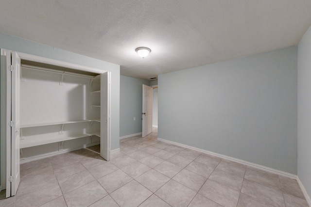 unfurnished bedroom with light tile patterned floors, a textured ceiling, and a closet