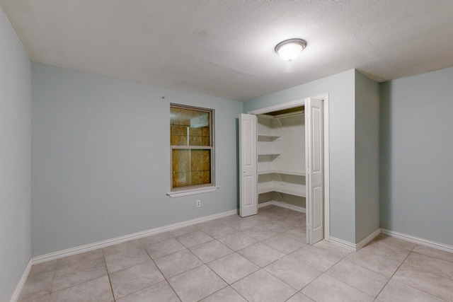 unfurnished bedroom featuring light tile patterned floors, a textured ceiling, and a closet