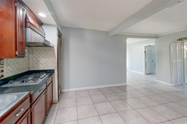 kitchen featuring stainless steel gas stovetop, light tile patterned floors, dark stone counters, and tasteful backsplash