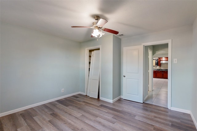 unfurnished bedroom with ceiling fan, a closet, and light wood-type flooring