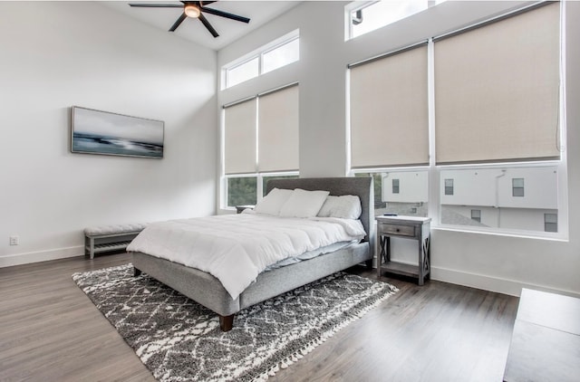 bedroom with ceiling fan, dark wood-type flooring, and a high ceiling