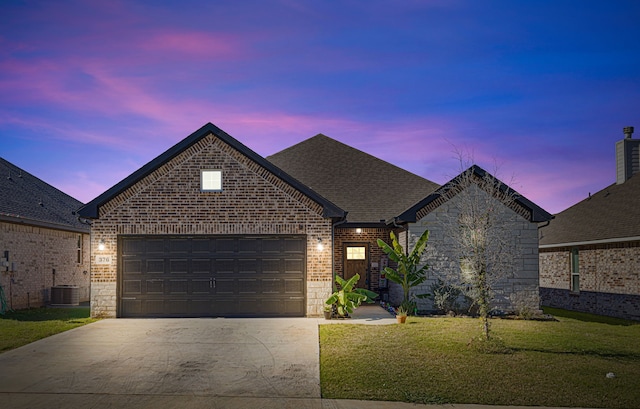 french provincial home featuring a yard, central AC unit, and a garage