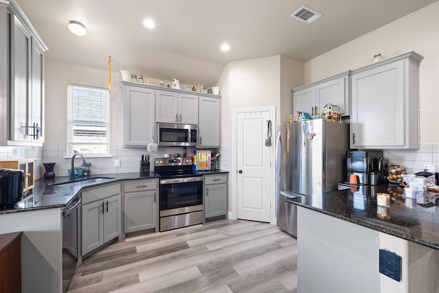 kitchen with decorative backsplash, sink, light hardwood / wood-style floors, and appliances with stainless steel finishes