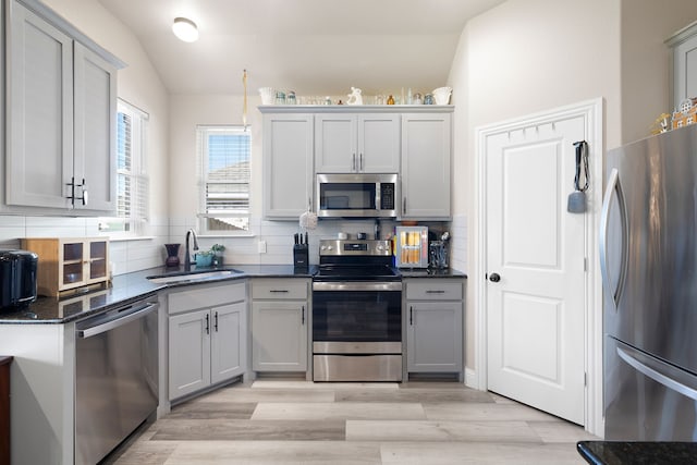 kitchen with backsplash, stainless steel appliances, vaulted ceiling, and sink