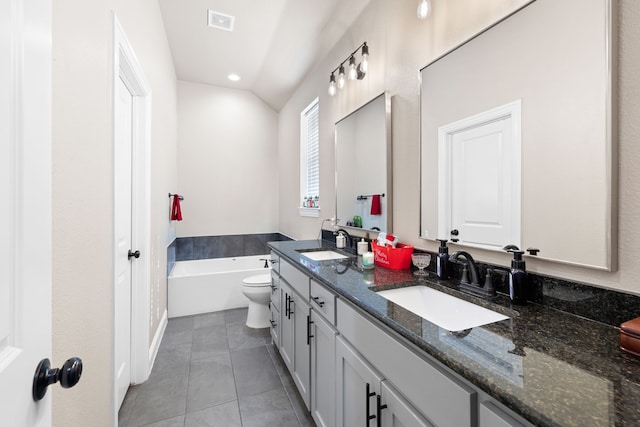 bathroom with vanity, vaulted ceiling, tile patterned flooring, toilet, and a tub