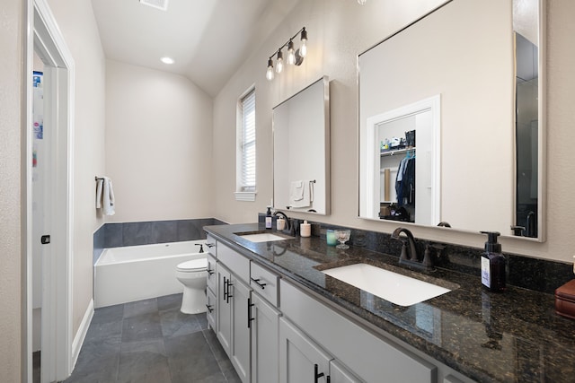 bathroom with tile patterned floors, toilet, vaulted ceiling, vanity, and a tub