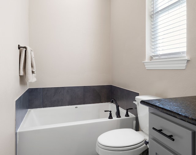 bathroom with vanity, a tub to relax in, and toilet