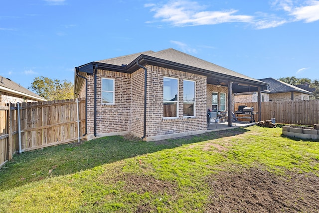 rear view of house with ceiling fan, a yard, and a patio