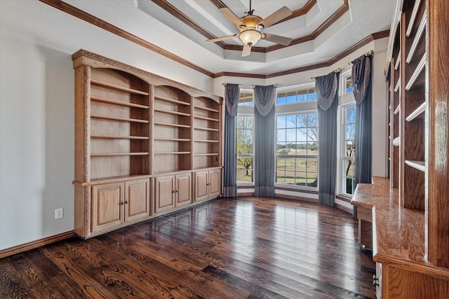 unfurnished office with a tray ceiling, dark wood-type flooring, ornamental molding, and ceiling fan