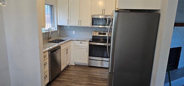 kitchen with white cabinets, sink, light stone countertops, appliances with stainless steel finishes, and dark hardwood / wood-style flooring