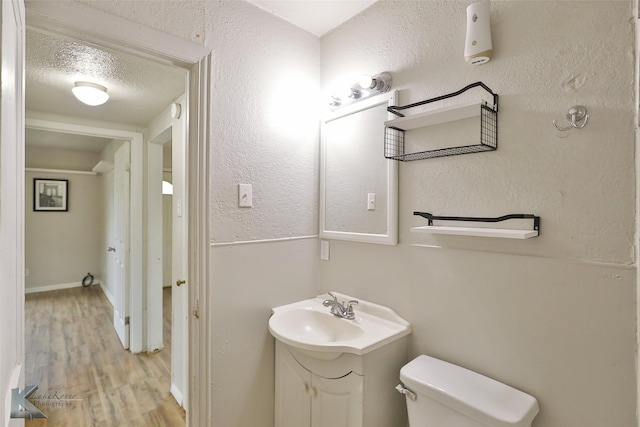 bathroom with vanity, wood-type flooring, toilet, and a textured ceiling