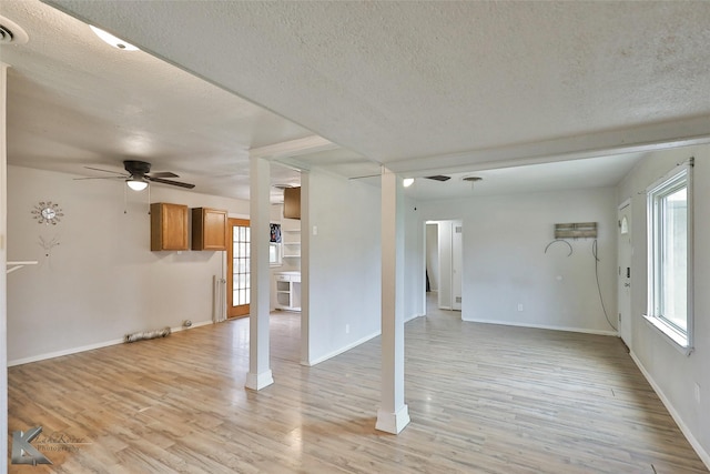 unfurnished living room featuring ceiling fan, light hardwood / wood-style floors, and a textured ceiling