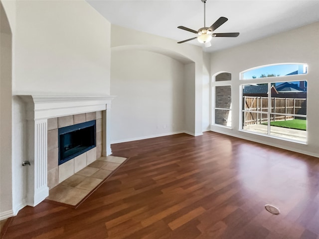 unfurnished living room featuring a tile fireplace, ceiling fan, and hardwood / wood-style flooring