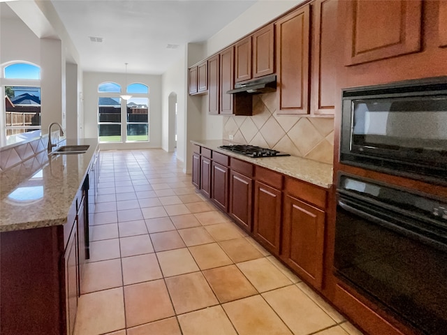 kitchen featuring tasteful backsplash, sink, black appliances, light tile patterned floors, and decorative light fixtures